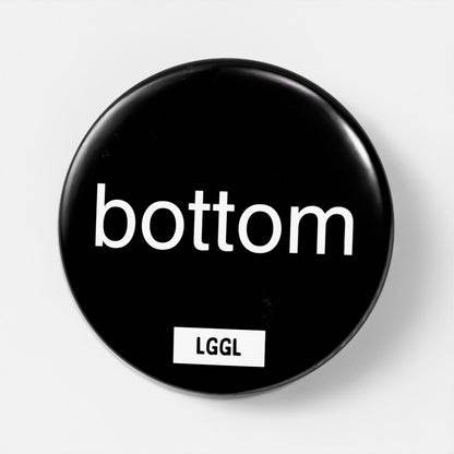 Black round kinky pin badge with "bottom" text